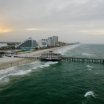A stunning aerial view of Daytona Beach's pier and coastline at sunset with vibrant ocean waves.
